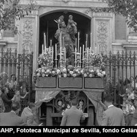 Curiosa imagen de San Cristóbal, obra de Martínez Montañés  transportado en un jeep militar cubierto por faldón con respiraderos y adorno de flores. En esta ocasión la imagen fue conducida hasta el Parque de María Luisa donde los vehículos públicos y particulares serían bendecidos. 10 de julio de 1958.  ©ICAS-SAHP, Fototeca Municipal de Sevilla, fondo Gelán