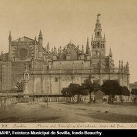 Plaza del Triunfo y fachada sur de la Catedral. Puerta de San Cristóbal en construcción según proyecto del arquitecto Fernández Casanova (1887-1895). Adosadas al muro catedralicio casetas de obra. En la plaza, el monumento al Triunfo y un puesto de aguas. ca. 1890. ©ICAS-SAHP, Fototeca Municipal de Sevilla, fondo Beauchy
