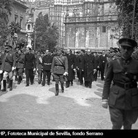 El jefe del Estado Francisco Franco por la Plaza del Triunfo tras asistir a los Santos Oficios en la Catedral en la mañana del Jueves Santo. Le acompañan el ministro de la Gobernación Ramón Serrano Súñer y el vicesecretario general del Movimiento Pedro Gamero del Castillo entre otras representaciones civiles y militares. 21 de marzo de 1940. ©ICAS-SAHP, Fototeca Municipal de Sevilla, fondo Serrano