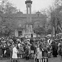 Vísperas de la celebración del Día de la Inmaculada bajo el monumento en la plaza del Triunfo. Un sacerdote dirige unas palabras a un grupo de escolares. 7 de diciembre de 1968. ©ICAS-SAHP, Fototeca Municipal de Sevilla, fondo Gelán