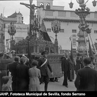 Paso neogótico del Cristo de las Misericordias y la Virgen de los Dolores de la Hermandad de Santa Cruz en la plaza Virgen de los Reyes. Al fondo, el convento de la Encarnación con los restos de la antigua Mezquita de los Osos y a la derecha, la fuente farola de José Lafita con sillas de enea apiladas. 1941. ©ICAS-SAHP, Fototeca Municipal de Sevilla, fondo Serrano