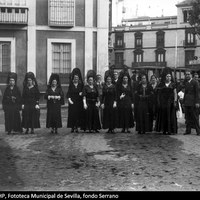 Mujeres ataviadas con mantilla española durante la Semana Santa en la Plaza del Duque de la Victoria. Detrás, además del tranvía de la línea 2, aparecen la fachada lateral del antiguo palacio de los Cavaleri, la calle Tarifa y el edificio de la familia Gómez y Pérez de León, obra de José Gómez Millán, con la Casa Kodak en la planta baja. 1933. ©ICAS-SAHP, Fototeca Municipal de Sevilla, fondo Serrano