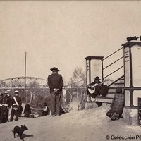 23. El cante de la tierra. Tocando la guitarra al pie de la escalinata de la pasadera del agua de Chapina. Al fondo, el puente del ferrocarril a Huelva. ©Colección Pérez Basso