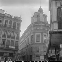 Chaflán con la torre del reloj del Palacio de Justicia en la esquina de la calle Almirante Apodaca con la calle Alhóndiga. En el entorno, peluquería Angelita, mercería Cruz, mercería Benito, estudio fotográfico Oaxaca y bar 6’40. 1971. ©ICAS-SAHP, Fototeca Municipal de Sevilla, fondo Serrano