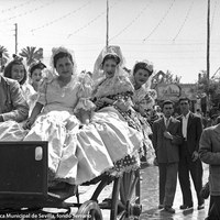 En coche de punto, varias jóvenes posan para el reportero en una Feria de 1950. A la derecha, la caseta de la peña El Chachi.