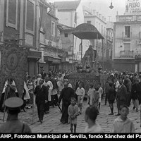 La Virgen de las Aguas de la parroquia del Salvador a su paso por la plaza Jesús de la Pasión. La plaza, denominada también del Pan, presenta ya el pavimento de adoquín instalado en 1913. Al fondo el antiguo edificio de almacenes de ropa confeccionada “Pedro Roldán”.  Aún no habían comenzado las obras del proyectado por José Espiau para la misma casa de tejidos. (1925-1926) ©ICAS-SAHP, Fototeca Municipal de Sevilla, fondo Sánchez del Pando 