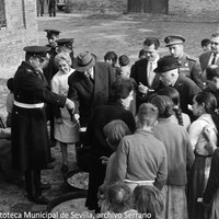 14. Visita de Pedro Gual Villalbí, ministro delegado del Gobierno, y Camilo Alonso Vega,  ministro de la Gobernación, al refugio habilitado en el Matadero Municipal. Diariamente la cercana factoría de HYTASA proveía de comidas. Les acompañan el gobernador civil Hermenegildo Altozano Moraleda y el alcalde Mariano Pérez de Ayala. 5 de diciembre de 1961 ©ICAS-SAHP, Fototeca Municipal de Sevilla, archivo Serrano